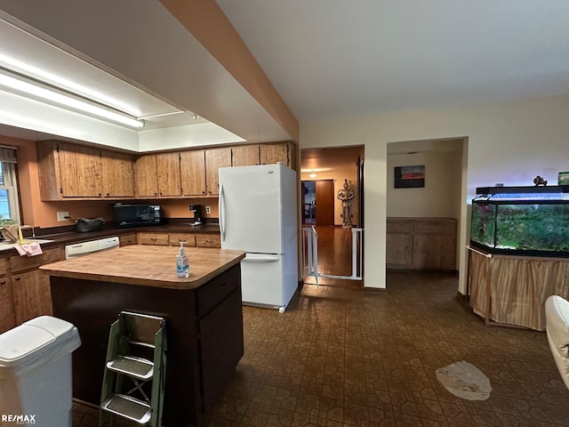 kitchen with white appliances, dark floors, brown cabinets, a center island, and wooden counters