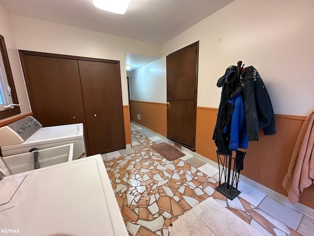 washroom with laundry area, wood walls, washer and clothes dryer, and wainscoting