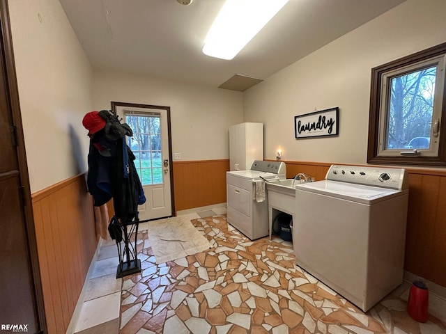 clothes washing area featuring laundry area, a wainscoted wall, washer and dryer, wood walls, and a sink