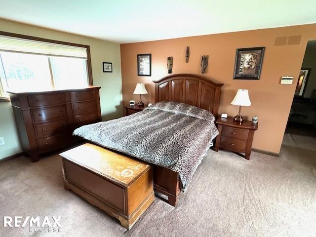 bedroom with light colored carpet, visible vents, and baseboards