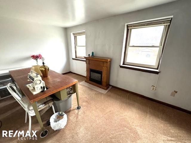 office space with a glass covered fireplace, carpet, and baseboards