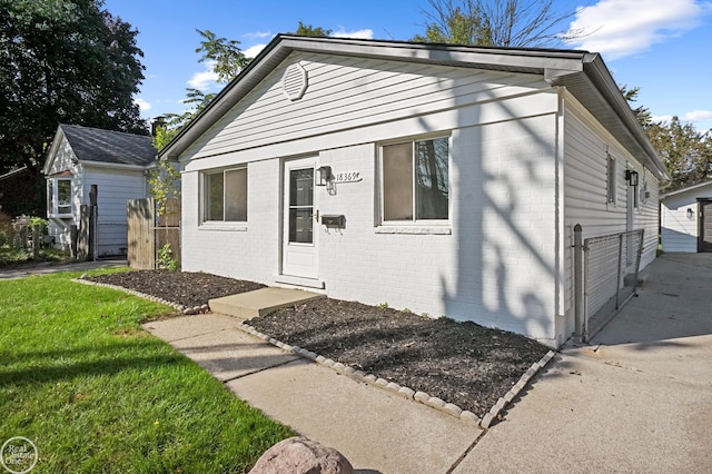 bungalow-style house featuring fence, a front lawn, and brick siding