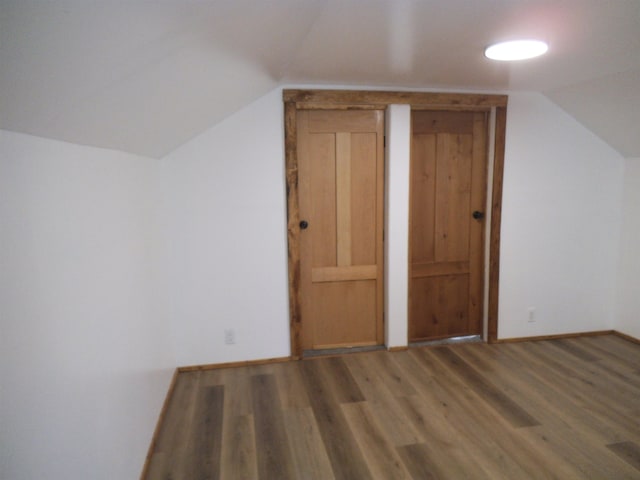 additional living space featuring vaulted ceiling, wood finished floors, and baseboards