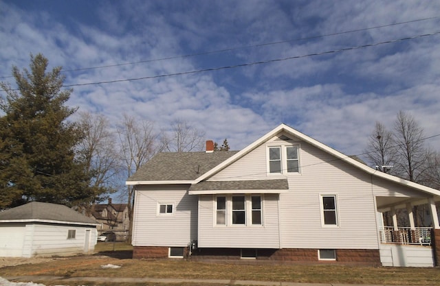 rear view of property with a shingled roof and a chimney