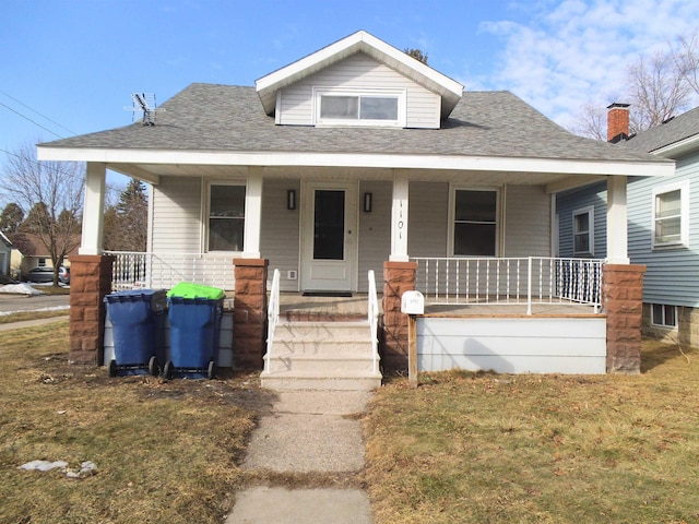 bungalow featuring a shingled roof, a porch, and a front yard