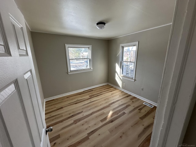 empty room featuring baseboards, visible vents, and light wood-style floors