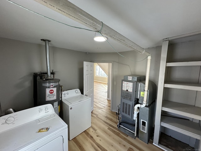 clothes washing area featuring light wood finished floors, water heater, laundry area, and washer and dryer