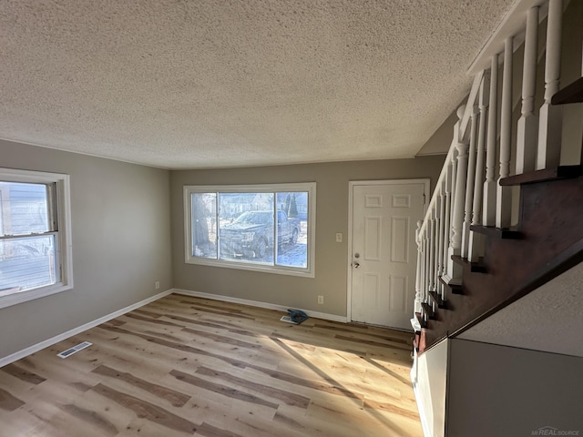 entrance foyer featuring visible vents, stairway, baseboards, and wood finished floors