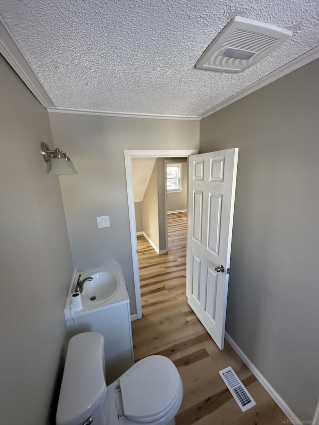 bathroom featuring toilet, visible vents, a sink, and wood finished floors