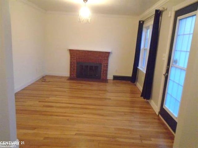 unfurnished living room featuring baseboards, a fireplace, wood finished floors, and crown molding