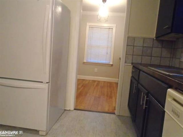 kitchen featuring white appliances, decorative backsplash, dark countertops, ornamental molding, and light wood-style floors