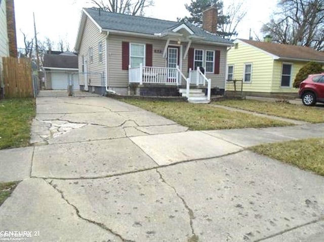 bungalow-style house featuring driveway, a chimney, covered porch, fence, and an outdoor structure