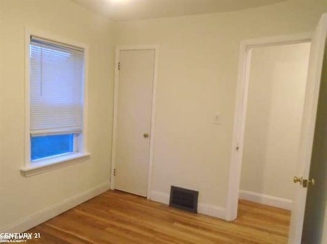 empty room with baseboards, visible vents, and wood finished floors