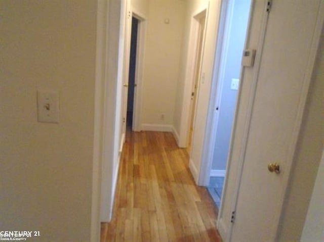 hallway featuring light wood-style flooring and baseboards