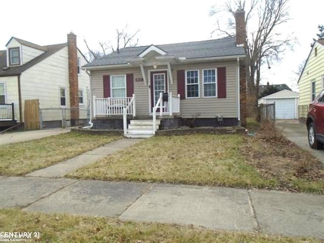 bungalow featuring a garage, a porch, an outdoor structure, and a front yard