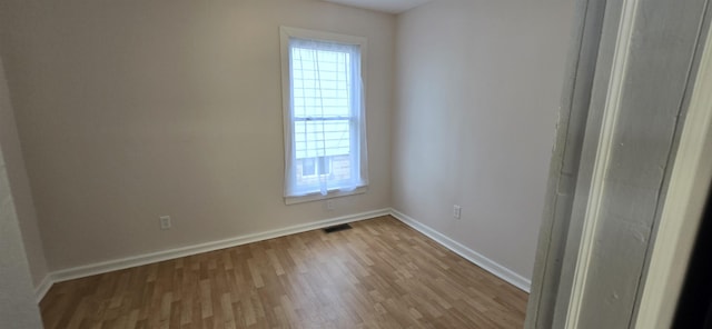 empty room with visible vents, baseboards, and wood finished floors