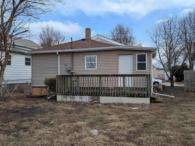 back of house with roof with shingles, fence, a chimney, and a wooden deck