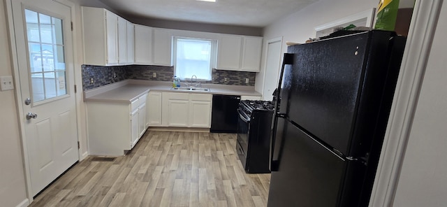 kitchen featuring a sink, light countertops, black appliances, light wood finished floors, and tasteful backsplash