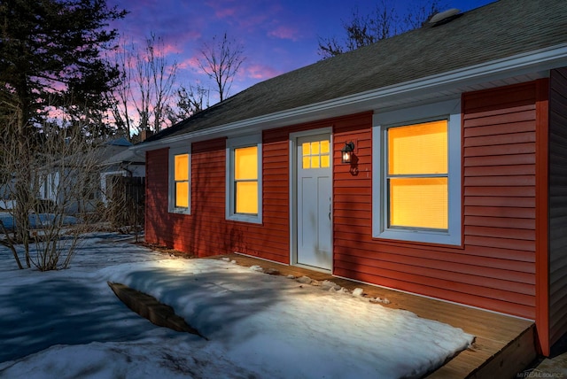 property exterior at dusk featuring roof with shingles