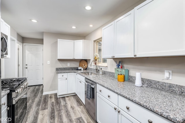 kitchen with stainless steel appliances, recessed lighting, light wood-style floors, white cabinetry, and a sink