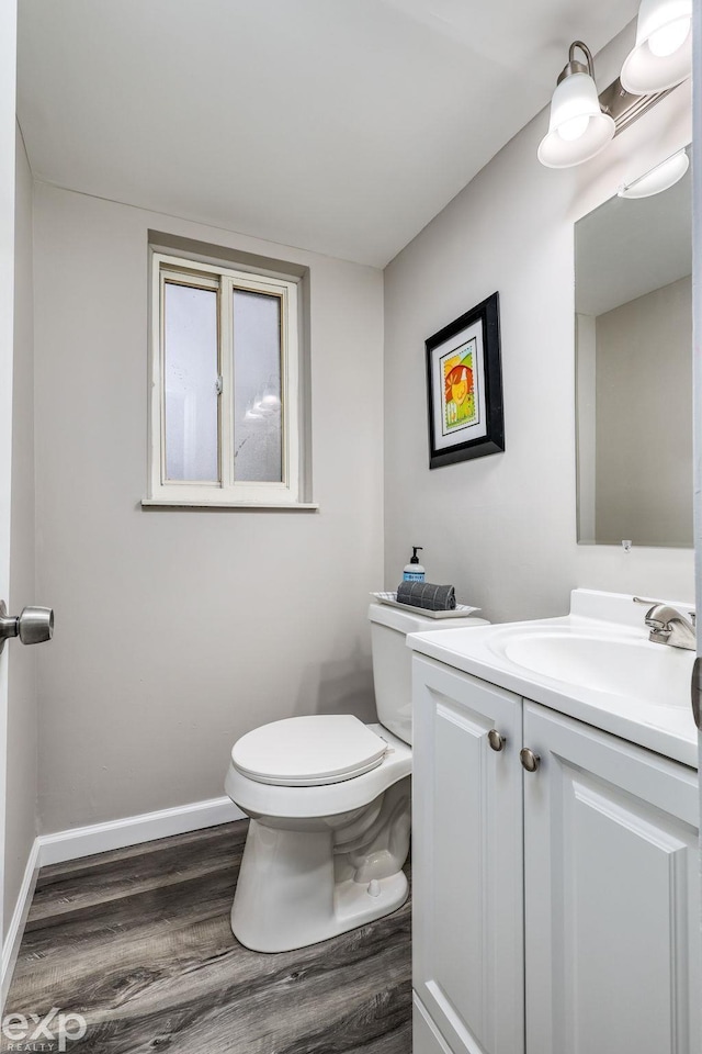 bathroom with toilet, baseboards, wood finished floors, and vanity