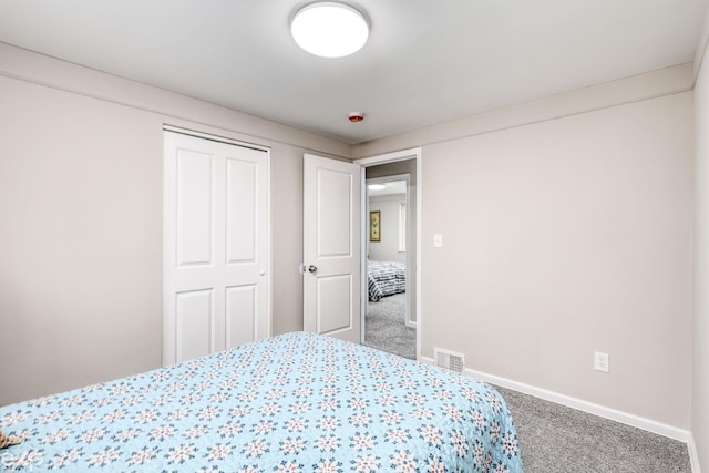 carpeted bedroom with visible vents, baseboards, and a closet