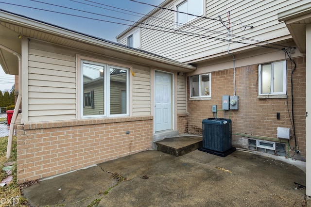 property entrance with brick siding and central AC unit