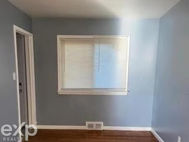 spare room featuring wood finished floors, visible vents, and baseboards