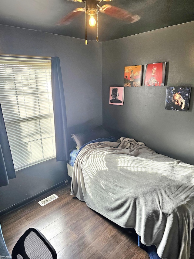 bedroom with multiple windows, wood finished floors, visible vents, and a ceiling fan