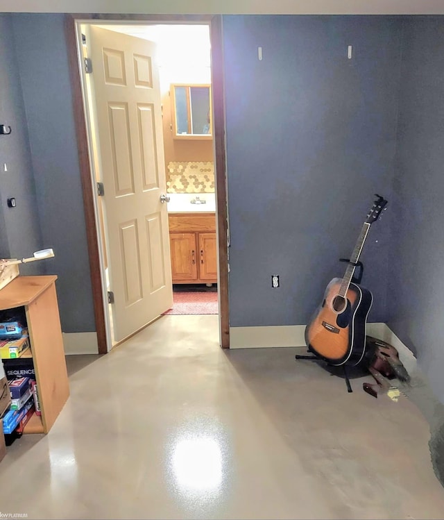 interior space with concrete floors, a sink, and baseboards