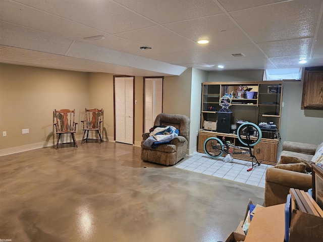 sitting room featuring finished concrete floors, a paneled ceiling, and baseboards