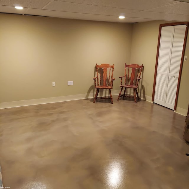 living area with concrete flooring, recessed lighting, a paneled ceiling, and baseboards