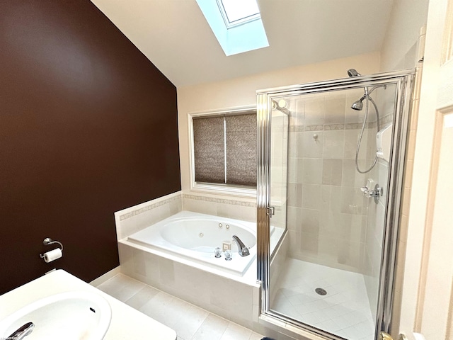 full bathroom featuring a whirlpool tub, a stall shower, vaulted ceiling with skylight, and a sink