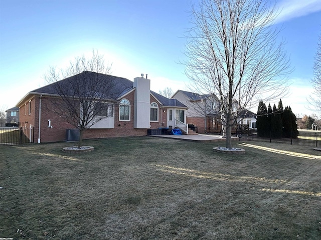 exterior space with brick siding, a chimney, central AC unit, fence, and a front lawn