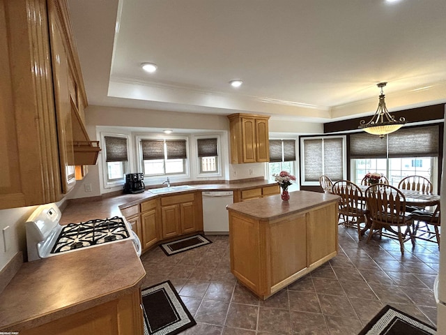 kitchen with a tray ceiling, white appliances, plenty of natural light, and a sink