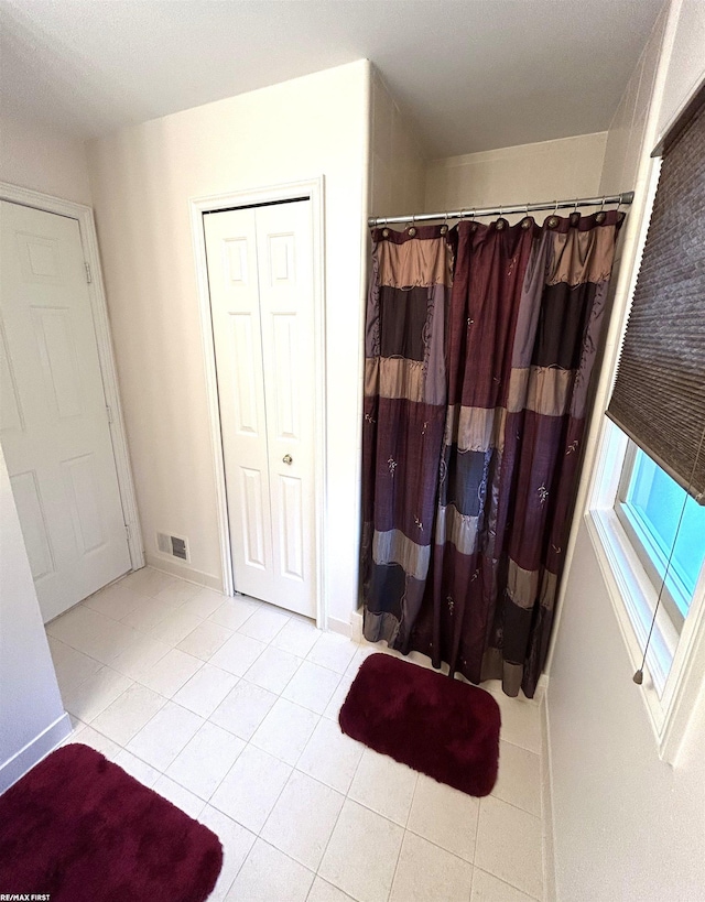 unfurnished bedroom with light tile patterned flooring, visible vents, and baseboards