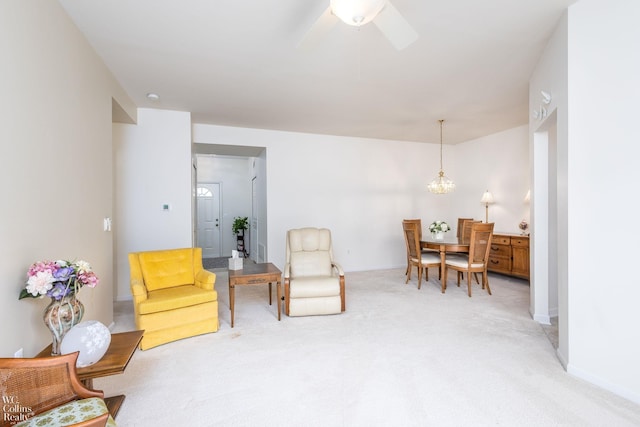 living area with light colored carpet, baseboards, and ceiling fan with notable chandelier