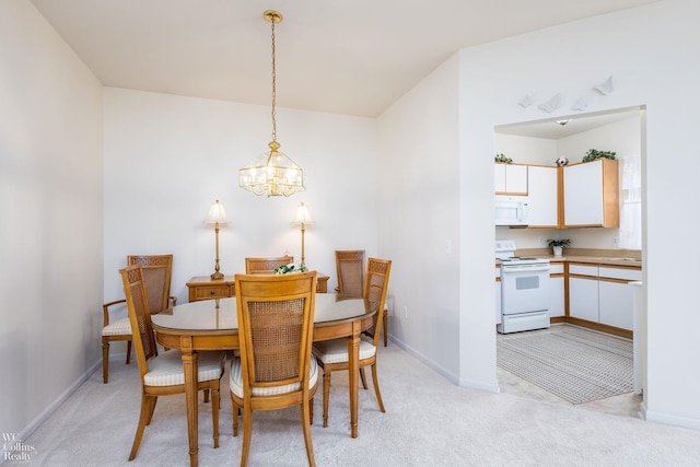 dining room with a chandelier, light colored carpet, and baseboards