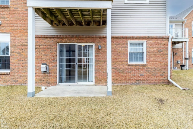 entrance to property featuring brick siding and a yard