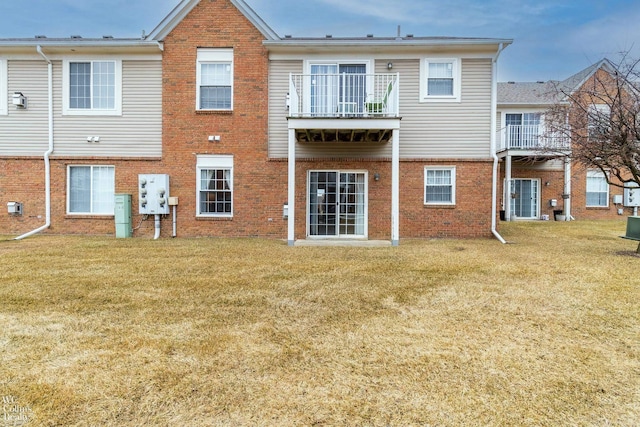 back of house featuring a yard, brick siding, and a balcony