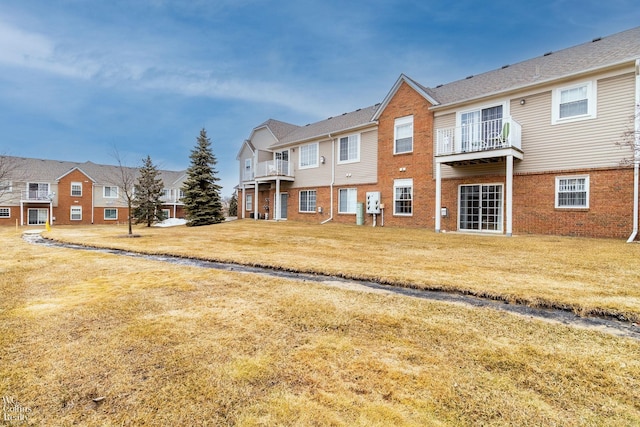 back of house with a yard, brick siding, and a residential view