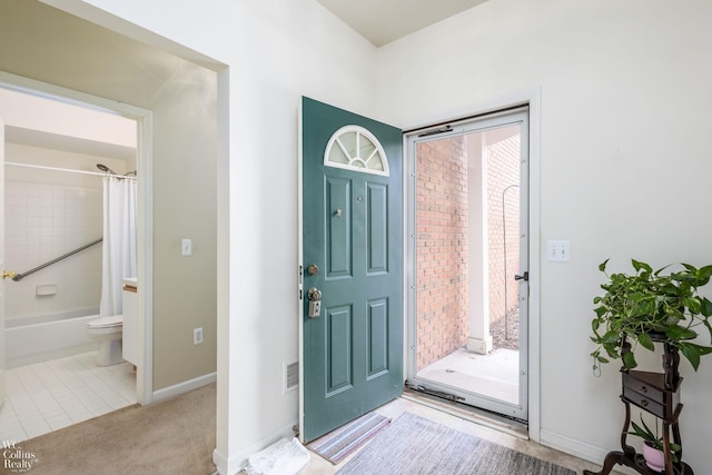 carpeted foyer entrance featuring tile patterned flooring and baseboards