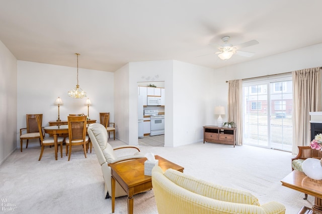 living room with light carpet, ceiling fan with notable chandelier, and baseboards