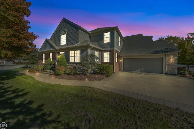 view of front of home with stone siding, an attached garage, concrete driveway, and a yard