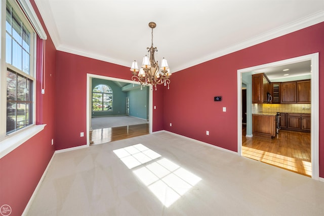 unfurnished dining area featuring a notable chandelier, carpet flooring, baseboards, and ornamental molding