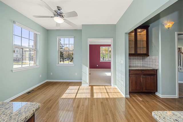 interior space with light wood-type flooring, visible vents, baseboards, and ceiling fan