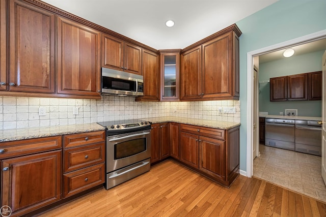 kitchen with light stone counters, stainless steel appliances, tasteful backsplash, and light wood finished floors