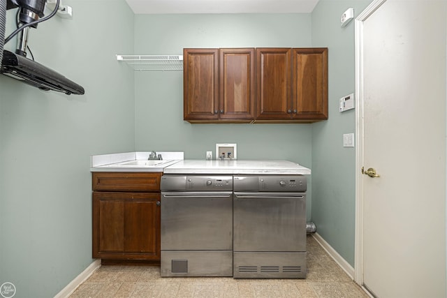 clothes washing area with a sink, baseboards, cabinet space, and washing machine and dryer