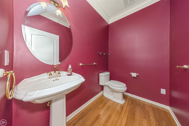 half bath with visible vents, crown molding, baseboards, toilet, and wood finished floors