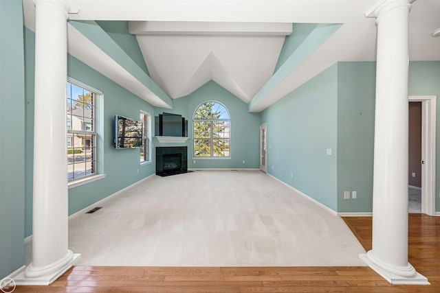 unfurnished living room featuring visible vents, baseboards, a tiled fireplace, lofted ceiling, and ornate columns